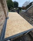 A flat roof area covered in brand new, light-coloured wooden boards, ready for the waterproof top layer to be put on.