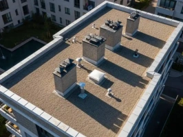 Drone view of a modern multi-story building with a detailed flat roof, including gravel surface, chimneys, and roof access hatch, showcasing the work of a flat roofing specialist in Chelmsford.