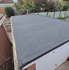 A finished flat roof covered in smooth, dark grey felt with neat white edging along the sides.