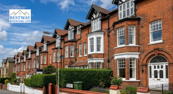 A row of traditional red-brick Victorian terraced houses with white window frames and shared guttering systems under a blue sky.
