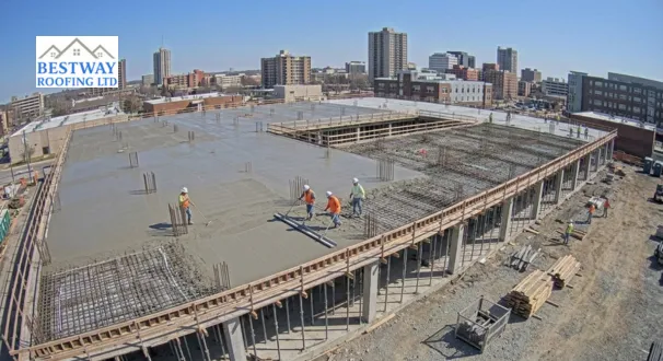 Construction workers levelling and smoothing poured liquid concrete for a reinforced concrete flat roof deck on a multi-storey commercial building site.