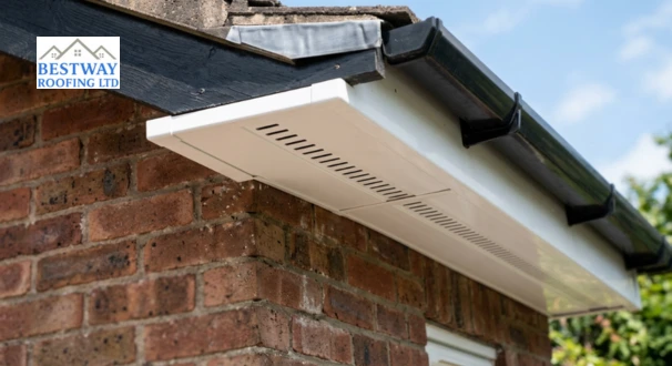 Close-up of a white vented uPVC soffit panel installed under a roofline overhang showing ventilation slots on a brick house